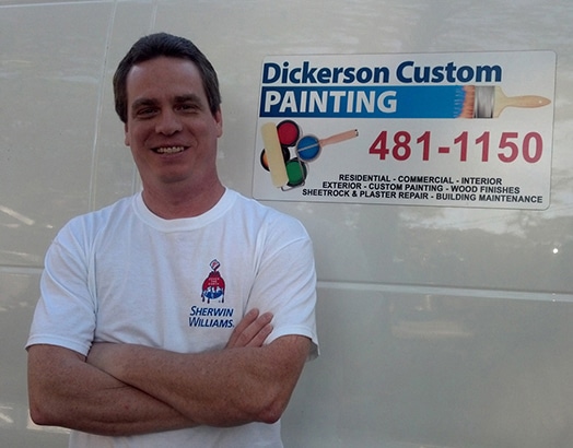Jonathan (John) Dickerson owner of Dickerson Custom Painting in Panama City Florida standing in front of his business sign with contact information and services listed